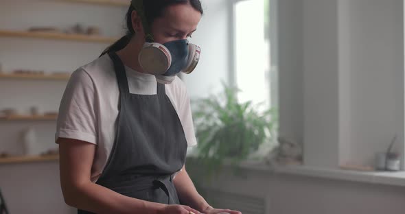 Woman in a Respirator and Apron Prepares Glaze in a Pottery Studio