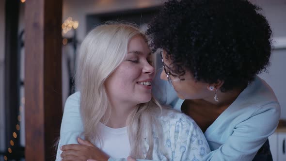 Young Girl Hugging Her Girlfriend From the Back and Kissing on a Forehead