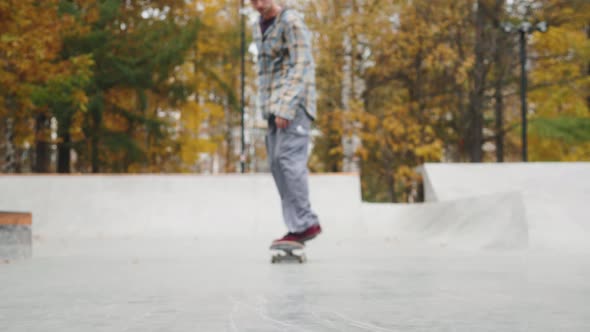 Skater Practicing in the Autumn Concrete Skate Park Making Tricks and Rides in Ramp