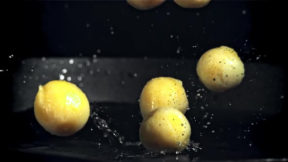 Peeled Potatoes Fall Into a Frying Pan with Splashes of Oil