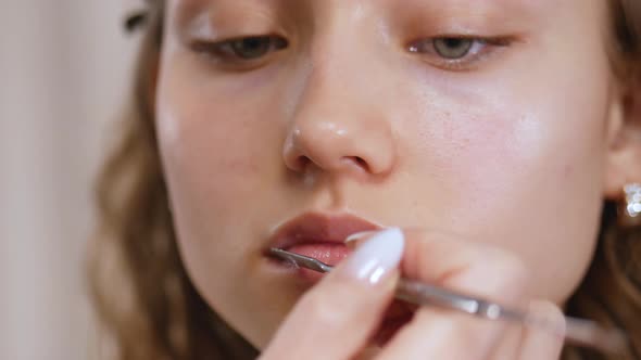 Preparing the Model's Skin for Applying Makeup. Lip Treatment with a Spatula and Lip Balm. Close Up.