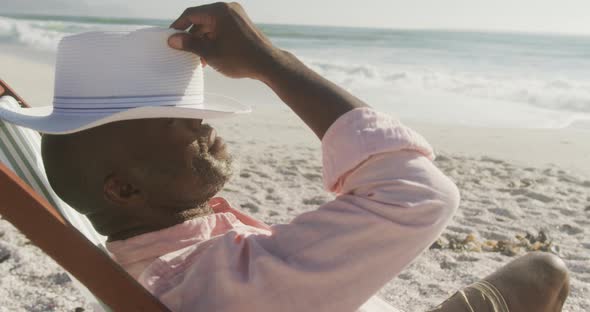 Senior african american man lying on sunbed on sunny beach