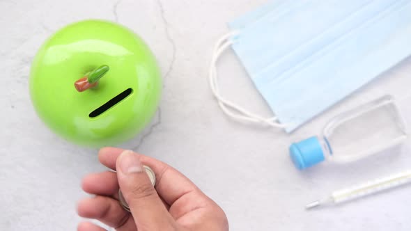 Saving Coins in a Jar with Face Mask and Hand Sanitizer on Table