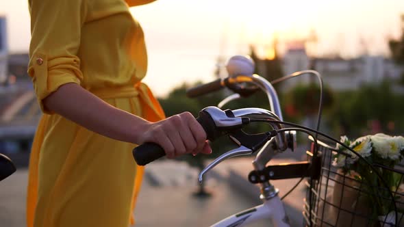 Closeup View of an Unrecognizable Woman's Hands Holding a Bicycle Handlebar with a Basket with