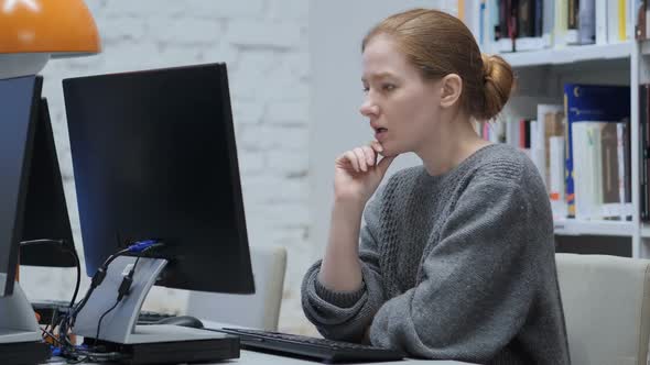 Thinking Redhead Woman Working on Laptop Sitting In Office