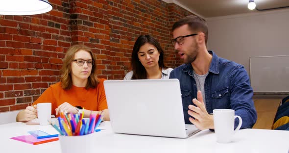 Group of executives discussing over laptop in the conference room