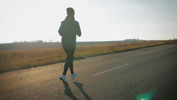 Young Fitness Sport Woman Running on Road at Sunset