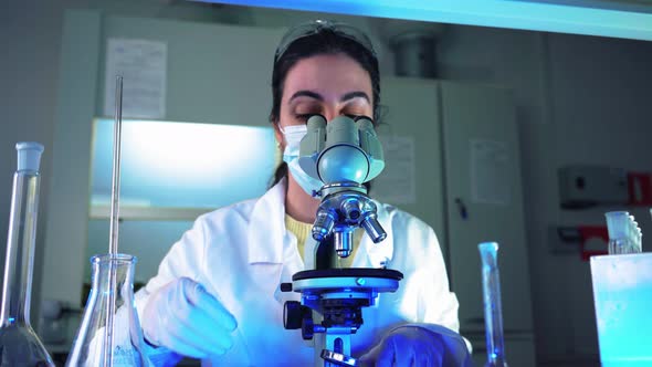 Female Microbiologist Looking Into Microscope in Medical Science Laboratory