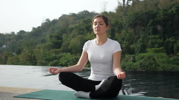 Novice Female Yogi Sitting in Lotus Position Back to the Pool