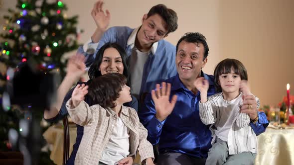 Positive Multiracial Family Waving Looking at Camera Smiling on Christmas Eve at Home
