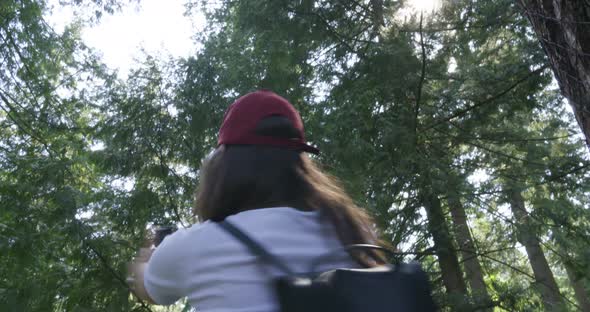 An excited, young woman having fun spinning in circles and taking a video with her camera in the for