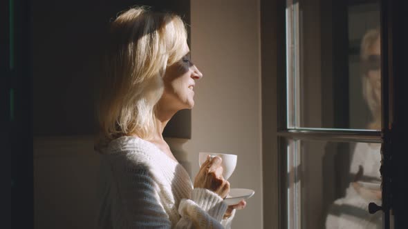 Portrait of Senior Woman with Cup of Coffee Looking Out of Window