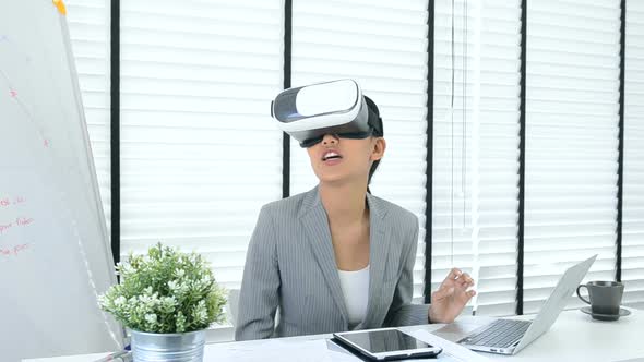 Asian woman use virtual reality glasses ( VR ) in her office
