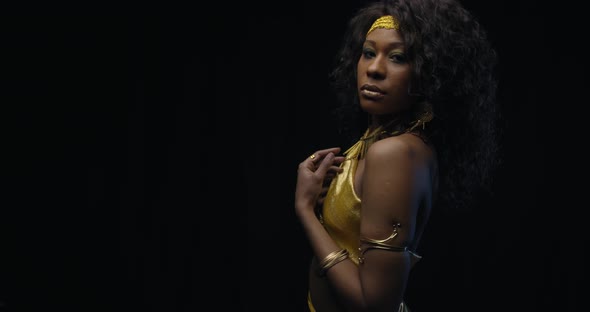 Gorgeous Black Woman Is Posing in Gold Dress and Jewelry Black Background