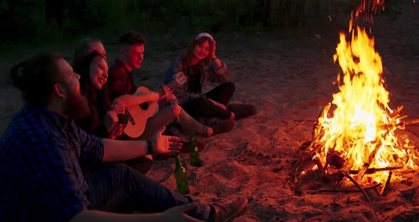 A Group of Friends Enjoying a Guitar Performance By the Campfire