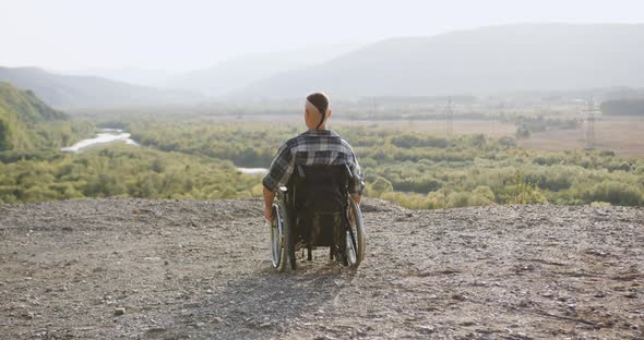 Man in Wheelchair with Great Willpower Celebrating Ascent on the Top of Hill with Raised Arms