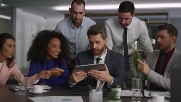 Diverse Executive Team Analyzing Data Using Tablet Device on Office Meeting