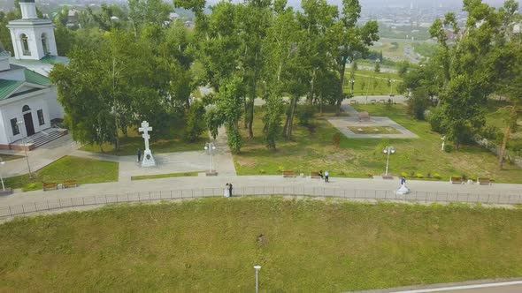 Just Married Couple Kisses Near Church in Park Aerial View