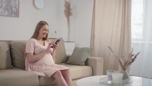 Smiling Expectant Woman With Smartphone