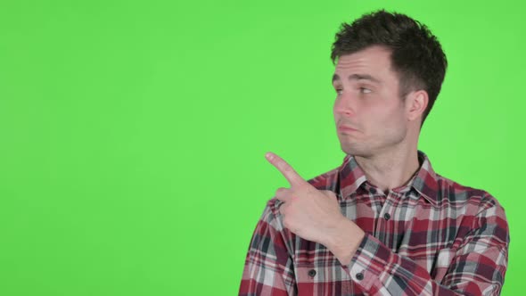 Portrait of Young Man Pointing Towards Product Green Chroma Screen