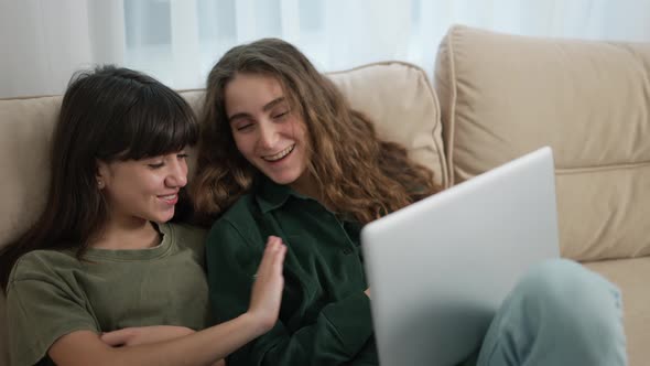 Two Pretty Caucasian Girls Having Fun While Watching Comedy Movie on Laptop on Couch in Room