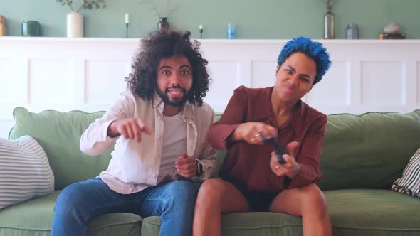 Young Arabian Man and African American Woman Play Video Games Sits on Sofa