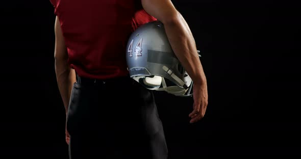 American football player holding a ball and head gear