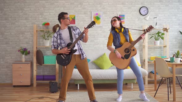 Young Woman and a Young Man Emotionally Play Guitars and Dance
