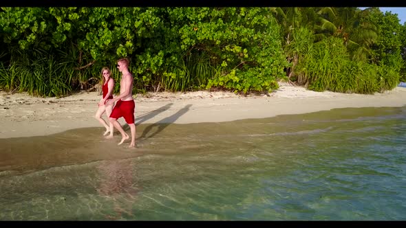 Guy and girl tanning on marine bay beach wildlife by blue green water with white sand background of 