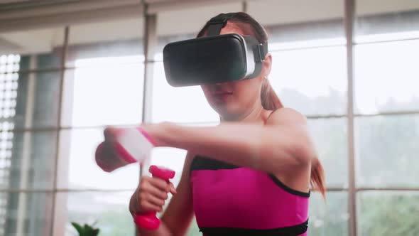 Young Asian woman wearing virtual reality glasses while working out at home.