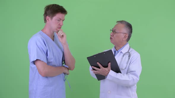 Stressed Mature Japanese Man Doctor with Young Man Patient Getting Bad News Together