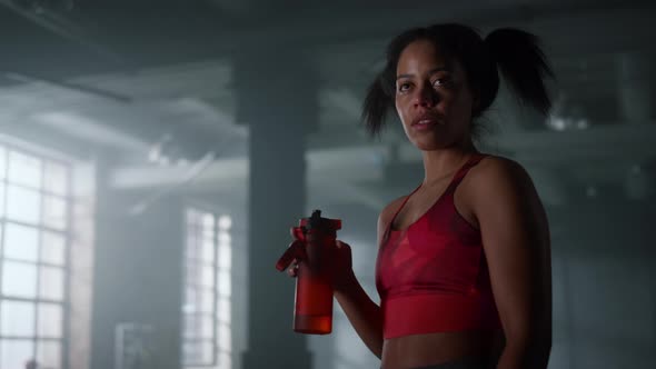 Tired Sportswoman with Water Bottle Standing in Gym