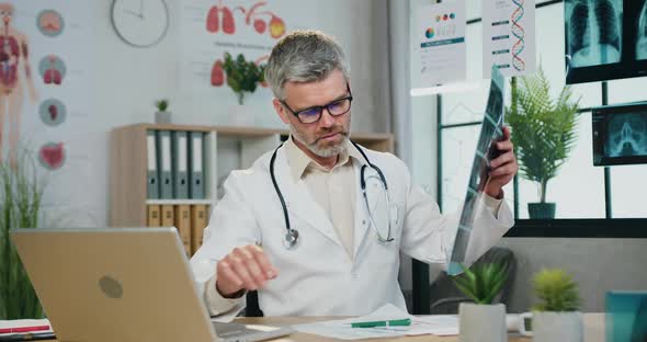 Doctor in Glasses Entering Results of X-ray Scan Diagnistic Into Computer