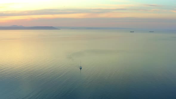 Colorful Sunset Over Sea Surface with Sailboat Aerial View