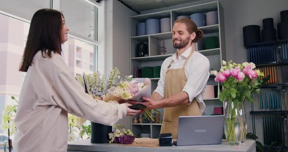 Woman Buying Flower Composition and Paying by Credit Card Using terminal.