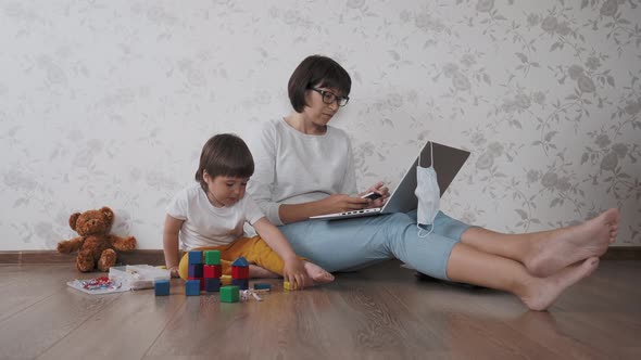 Mom and Son Sit at Home Quarantine Because of Coronavirus COVID19. Mother Remote Works with Laptop