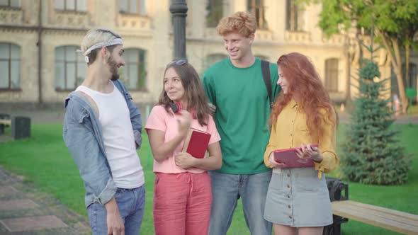 Camera Approaches To Group of Happy Young University Students Standing on Campus. Caucasian Men and