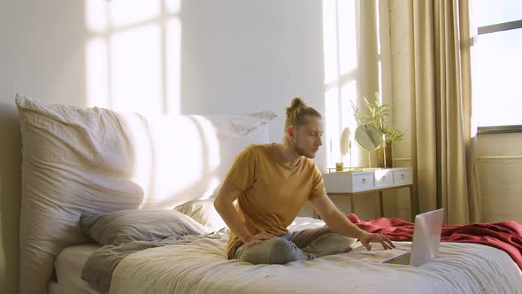 Young Man Chooses an Online Meditation Tuturial and Begins to Meditate