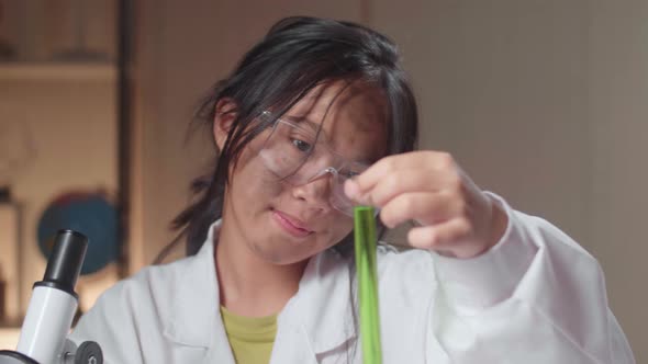 Young Scientist Girl With Dirty Face Looking At Microscope And Liquid In Test Tube