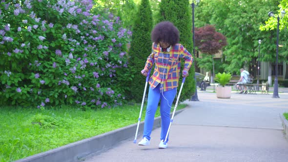 African American Woman with an Afro Hairstyle with a Broken Leg on Crutches