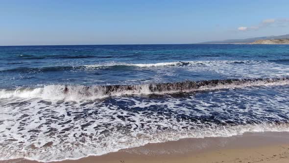 Camera Moves Along Sandy Summer Beach with Foamy Dark Blue Waves Rolling In. Sunny Day on Majestic