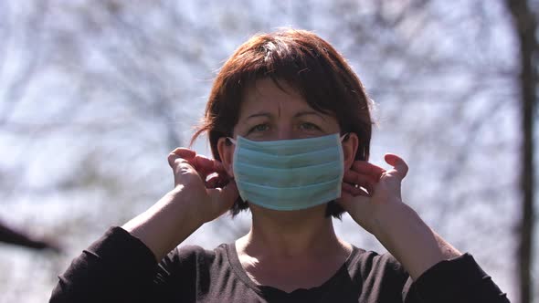 Woman Takes on Medical Mask. Breathes Deeply and Looking at Camera on Green Background. Health Care