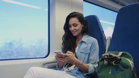 Happy Young Female Tourist Using Smartphone During Trip