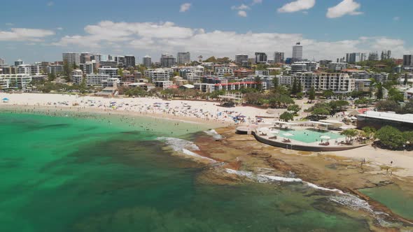 Aerial drone footage of ocean waves on a busy Kings beach, Caloundra, Australia