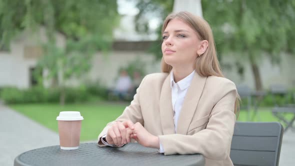 Serious Young Businesswoman Looking Towards Camera in Outdoor Cafe