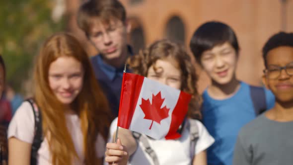 Group of Adorable Mixed Race Schoolkids with Canadian Flag Outside School Building