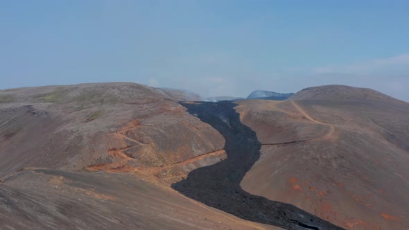 Aerial Circling Around Black Lava River Flowing Between Mountains in Fagradalsfjall Iceland Day