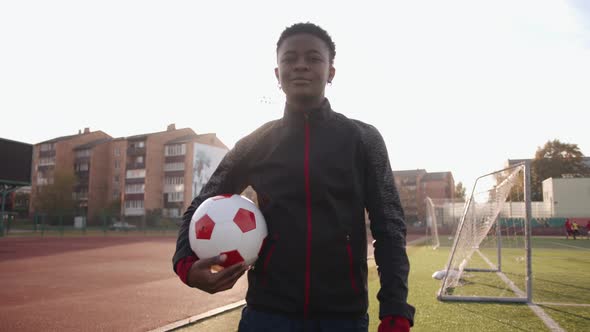 An Energetic Young Black Girl in a Sports Uniform Goes Across the Soccer Field with a Ball in Her