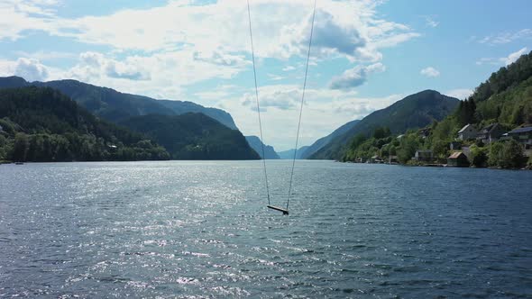 Tall spectacular swing hanging in front of mighty Norwegian fjord Veafjord - Amazing panoramic fjord