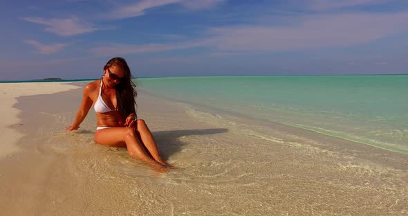 Pretty beauty model on holiday in the sun on beach on sunny blue and white sand 4K background